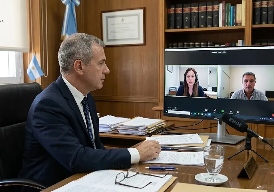 Juez en su despacho participa en una audiencia por videoconferencia con una abogada y un testigo.
